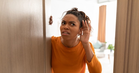 Lady Listening Standing In Opened Door At Home